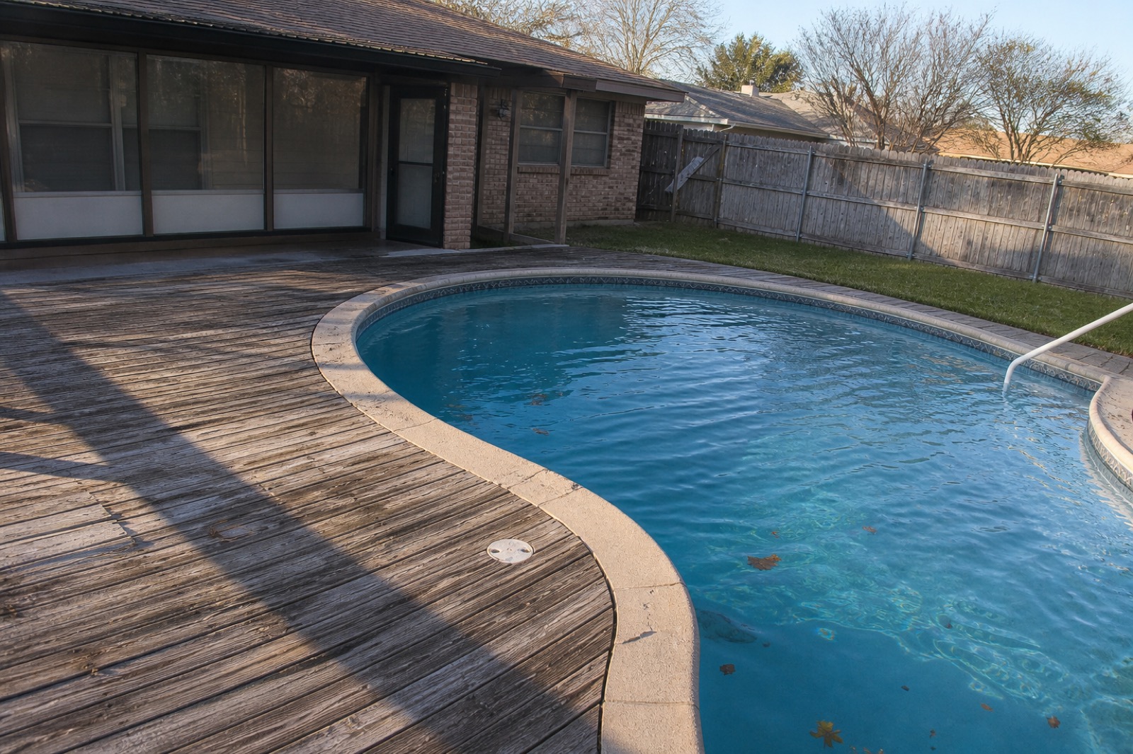 Residential pool on a weathered cedar deck in a Garland backyard, late afternoon